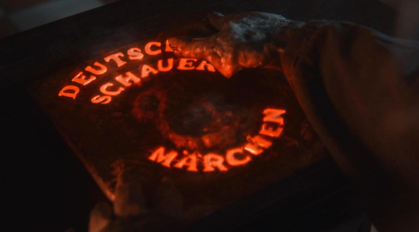 Glühender Schriftzug Deutsche Schauern Märchen auf einer dunklen Platte im Dunkeln berührt.