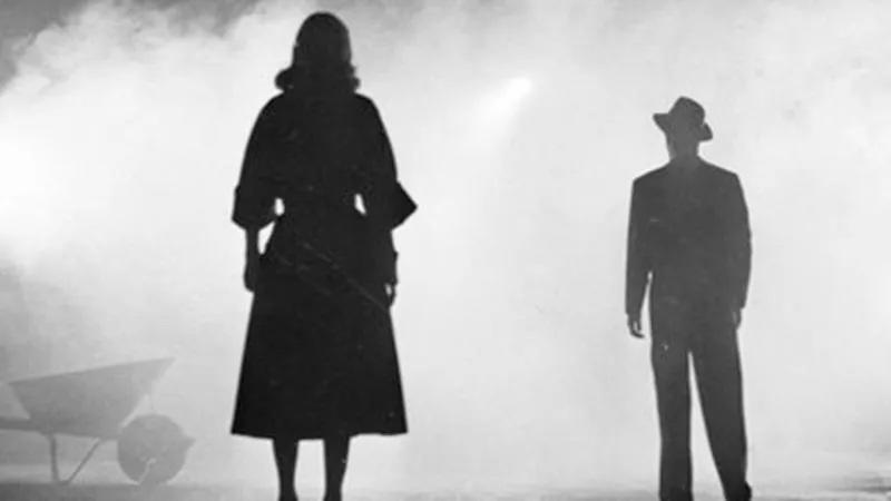 Schwarz-Weiß-Bild von zwei Personen in Mänteln, die im hellen Nebel stehen.