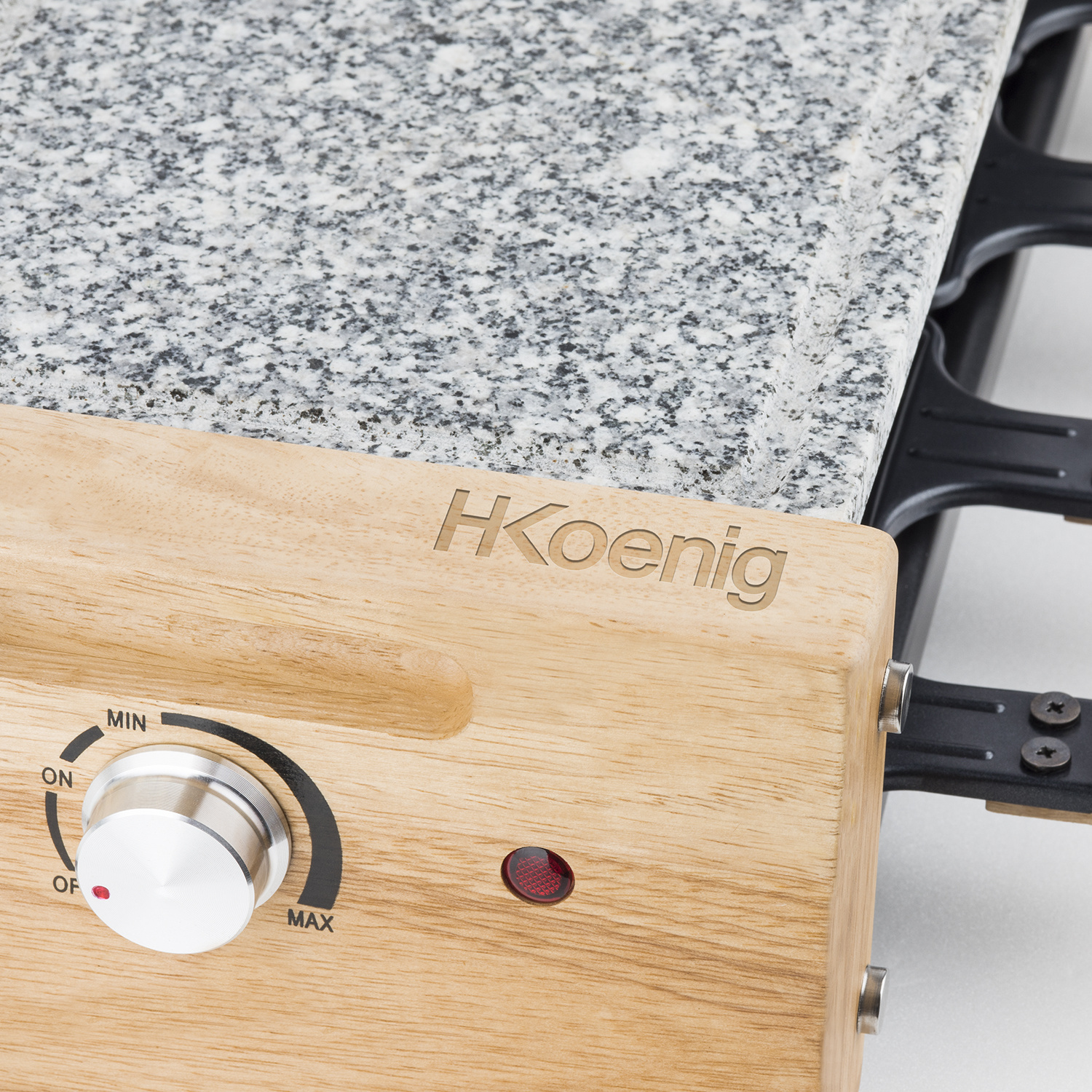 Primo piano di una griglia per raclette con base in legno, logo H.Koenig, manopola e piastra in granito.