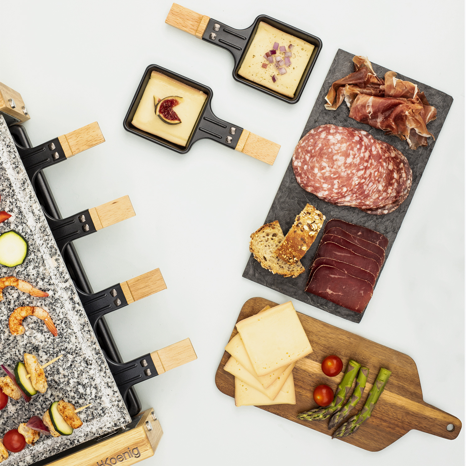 Raclette con piastra in pietra, padelle con formaggio, ardesia con salumi e tagliere di legno con formaggio e asparagi.