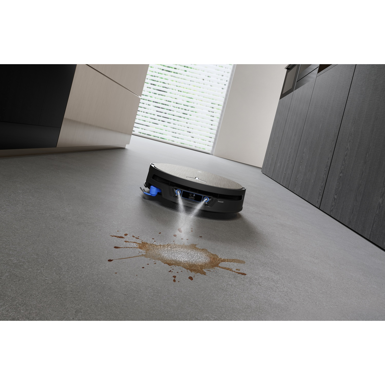 Un robot aspirapolvere spruzza acqua su una macchia di caffè sul pavimento.