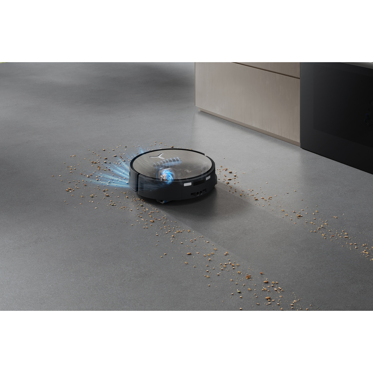 Un robot aspirapolvere nero pulisce un pavimento grigio con chicchi di caffè in cucina.