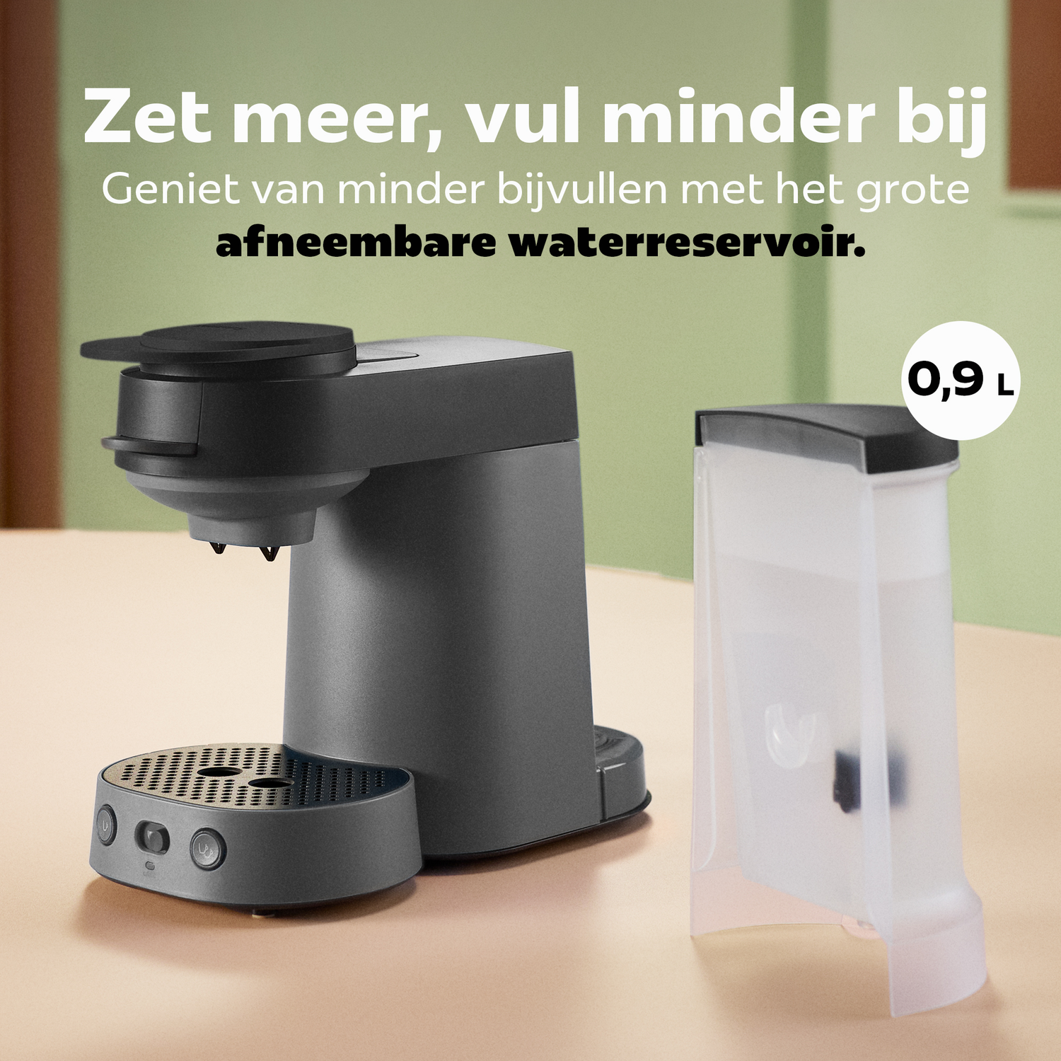Een grijze koffiemachine staat op een tafel naast een apart, afneembaar waterreservoir van 0,9 liter.