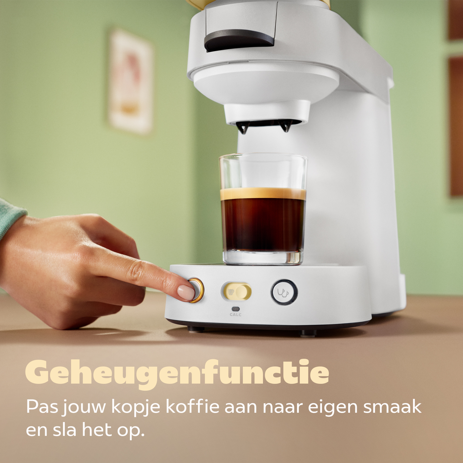 Een hand drukt op een knop van een witte koffiezetapparaat.