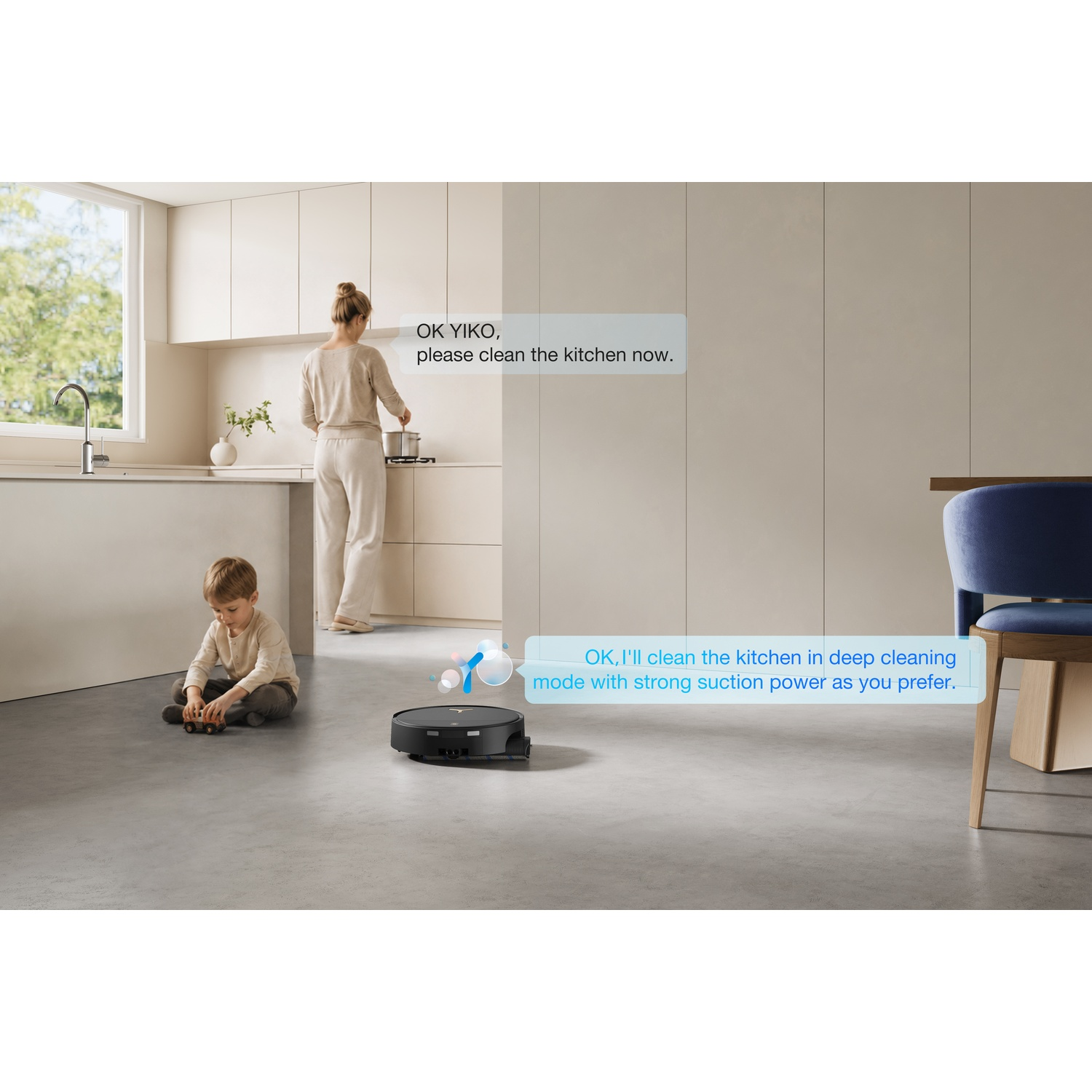 Una donna parla con un robot aspirapolvere nella sua cucina mentre un bambino gioca sul pavimento.
