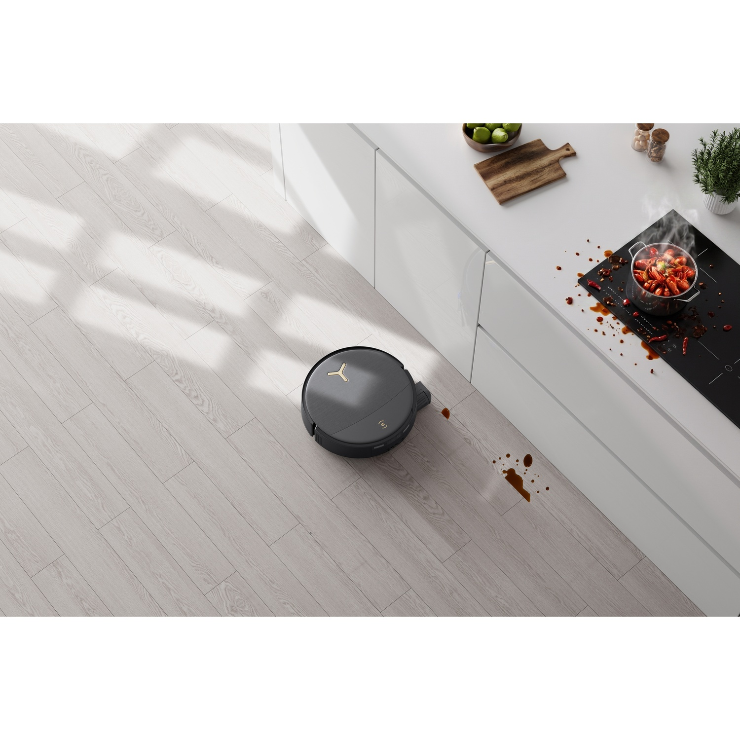 Un robot aspirapolvere scuro pulisce un pavimento in legno in una cucina moderna vicino a una macchia.