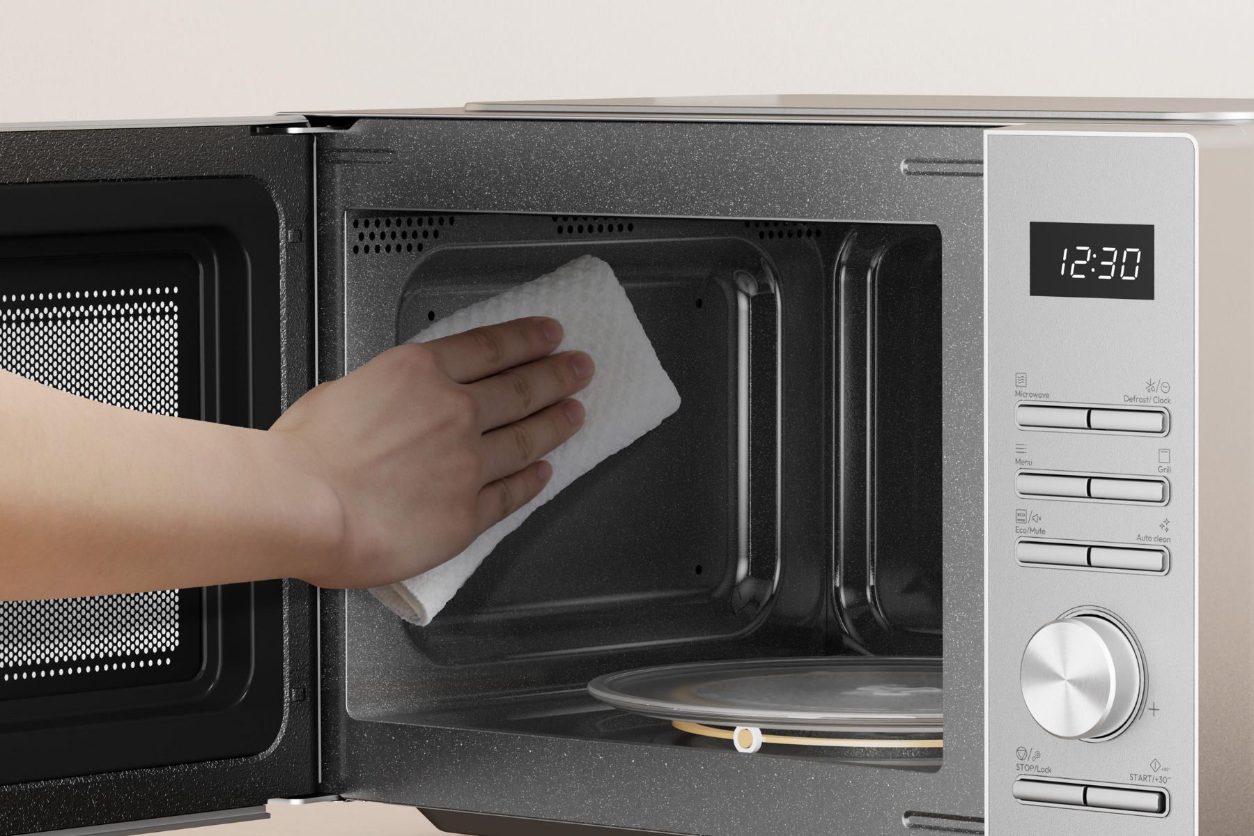 Una mano usa un paño blanco para limpiar el interior de un microondas abierto.