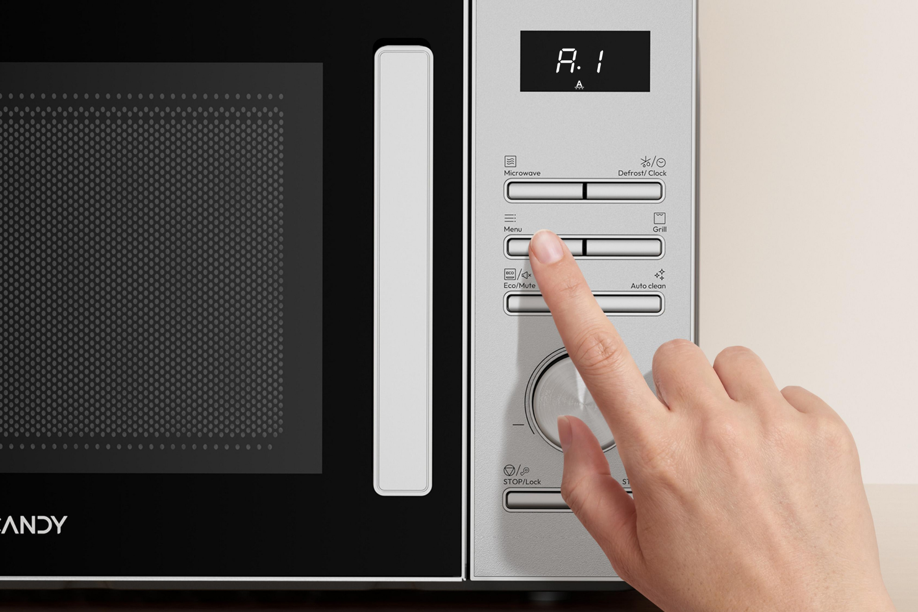 Mano presionando un botón en el panel de control de un microondas plateado.