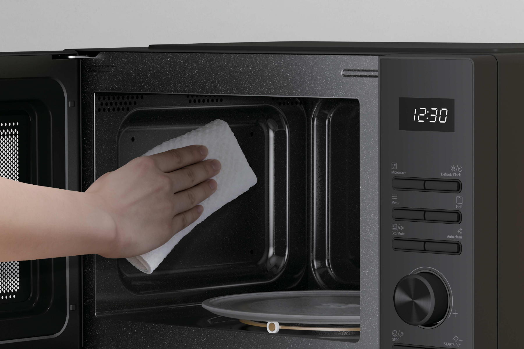 Una mano usa un paño blanco para limpiar el interior de un microondas negro abierto.