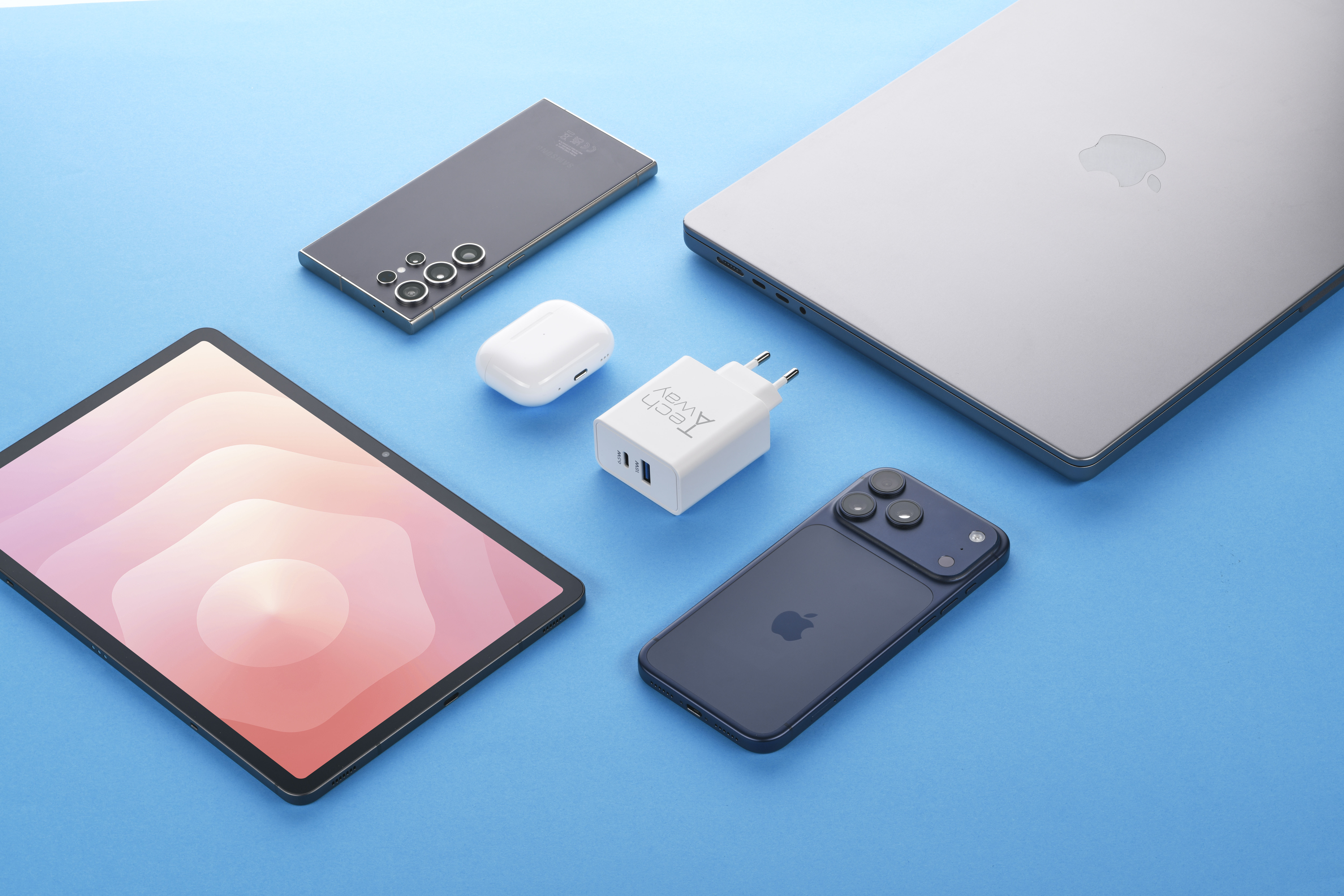 Verschiedene Tech-Geräte wie Laptop, Smartphone, Tablet, Ohrhörer und ein Ladegerät auf blauem Hintergrund.