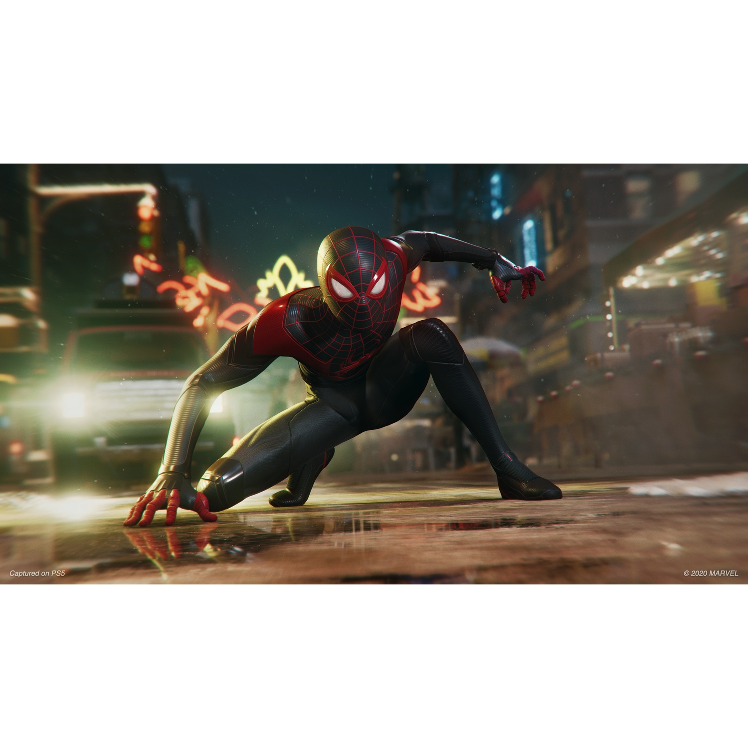 Miles Morales en costume noir et rouge accroupi sur de l'asphalte mouillé la nuit avec des lumières vives.