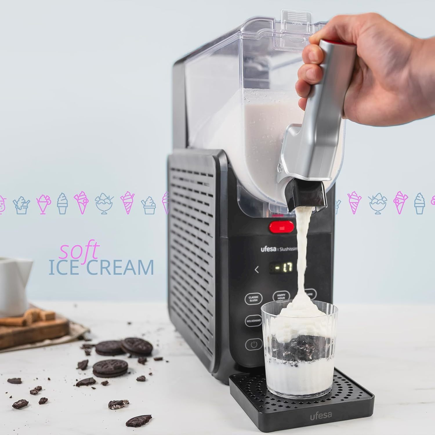 Una mano aziona il distributore di una macchina pergelato versando gelato soffice in un bicchiere con biscotti.