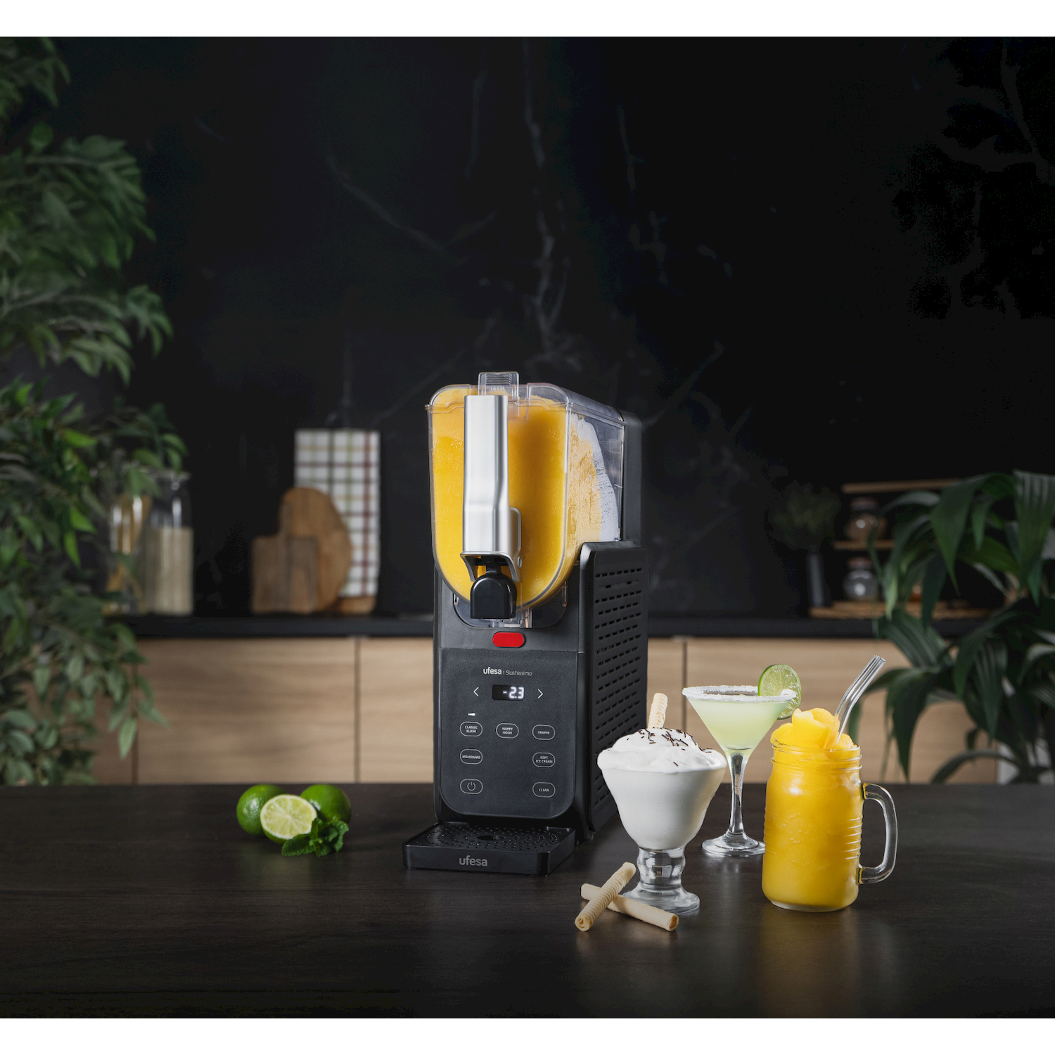 Macchina per granite su tavolo di legno con lime, gelato, cocktail e bevanda gialla.