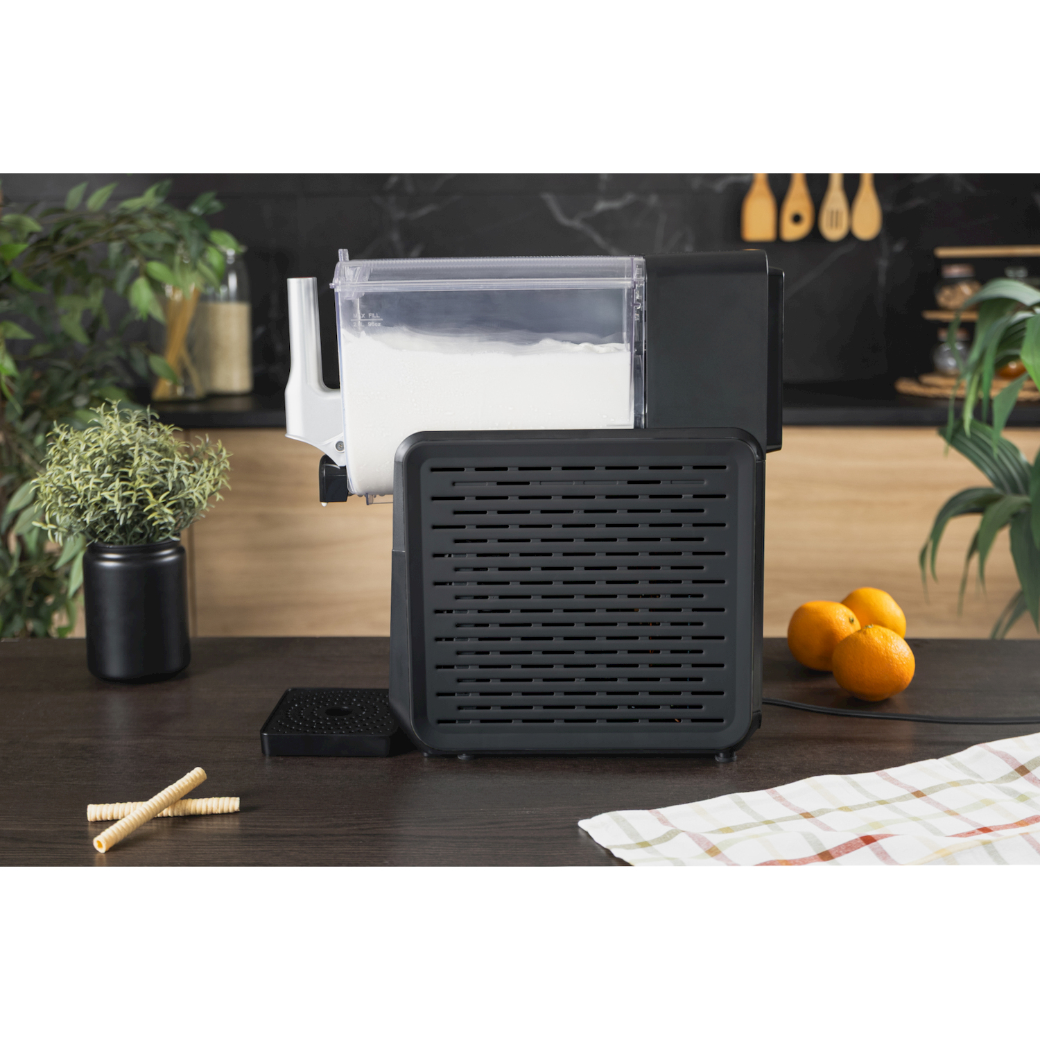 Elettrodomestico da cucina nero con contenitore trasparente pieno di farina su un tavolo di legno.