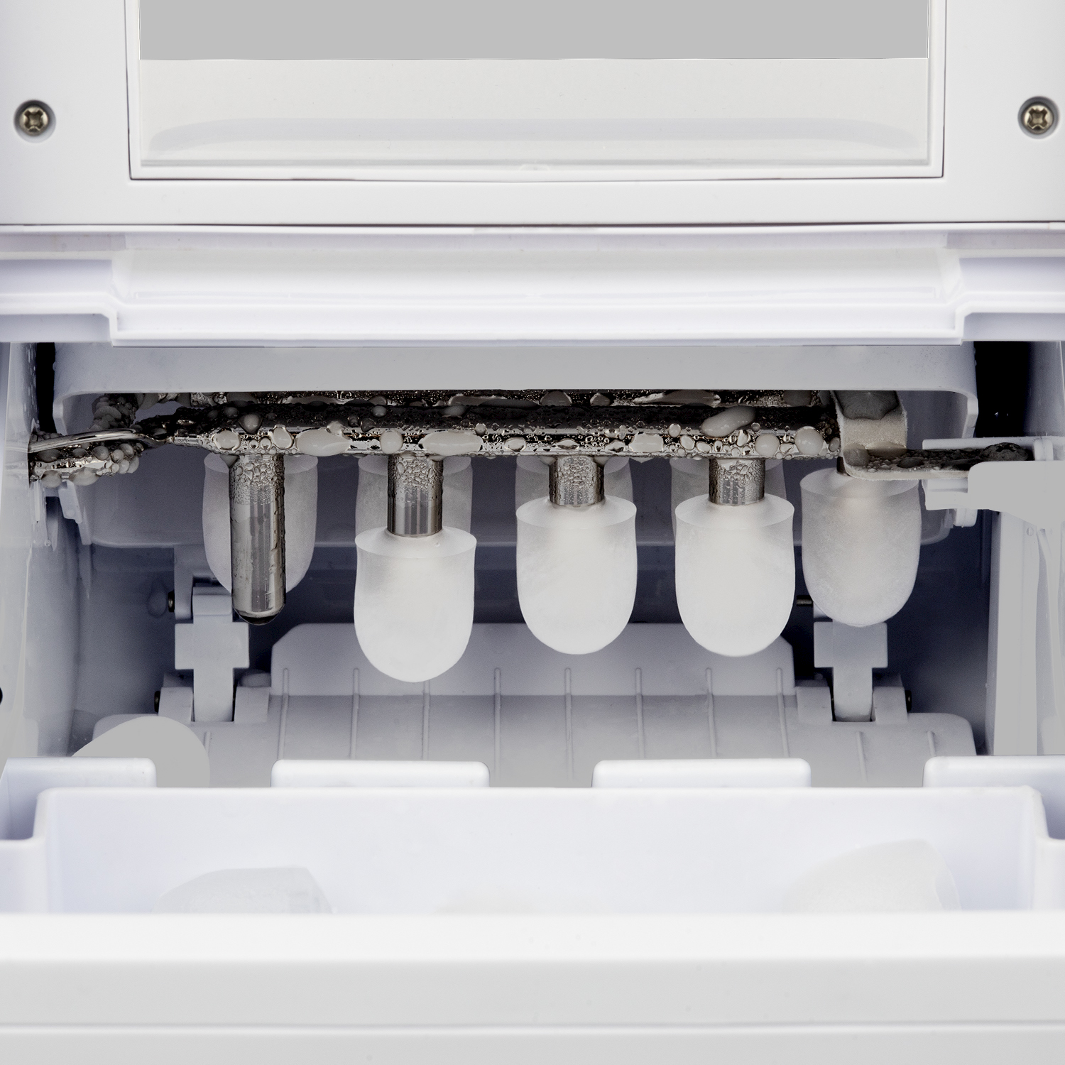 Primo piano di una macchina per il ghiaccio con perni metallici che formano cubetti.