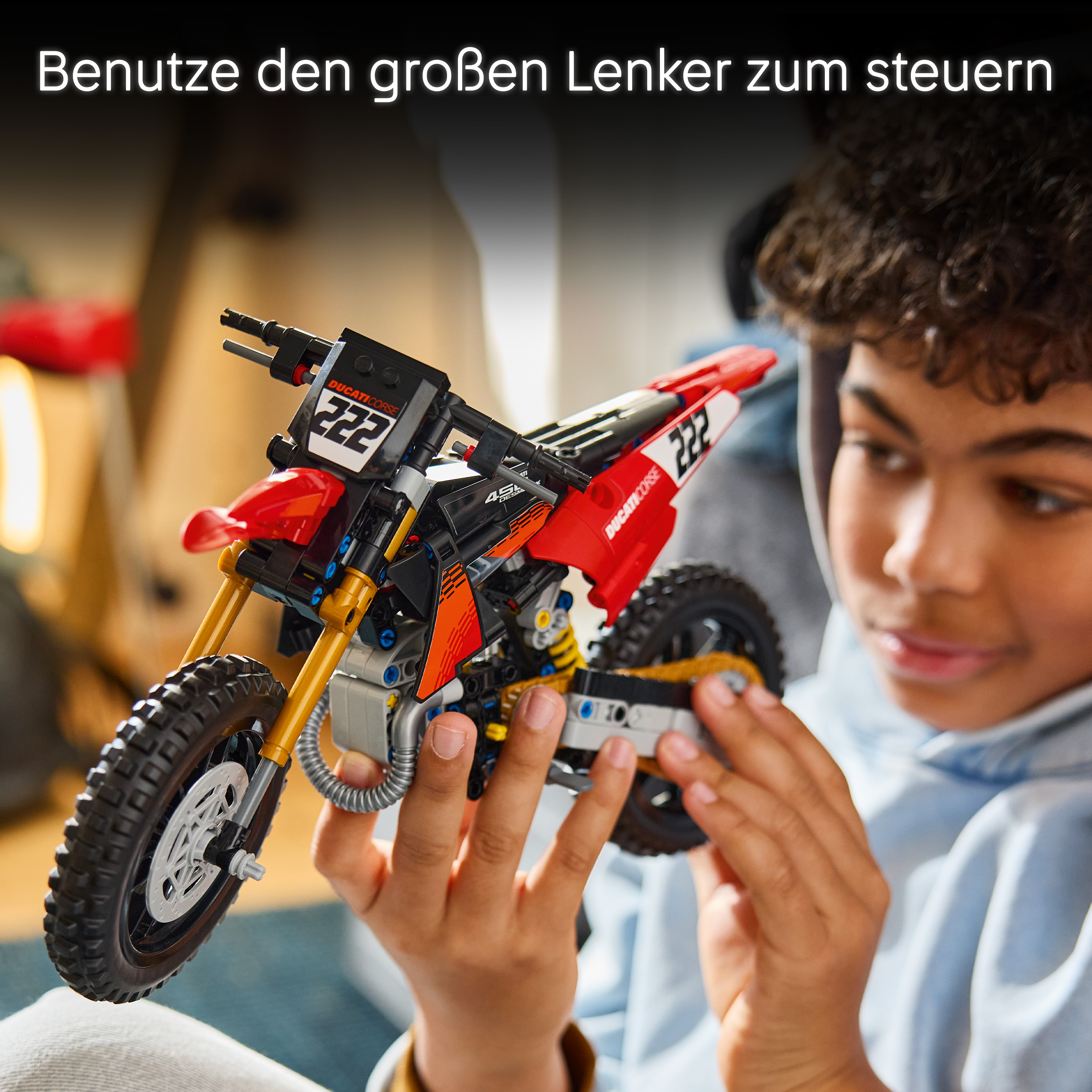 Ein Junge hält ein rotes Lego Technic Ducati-Motorrad in den Händen.