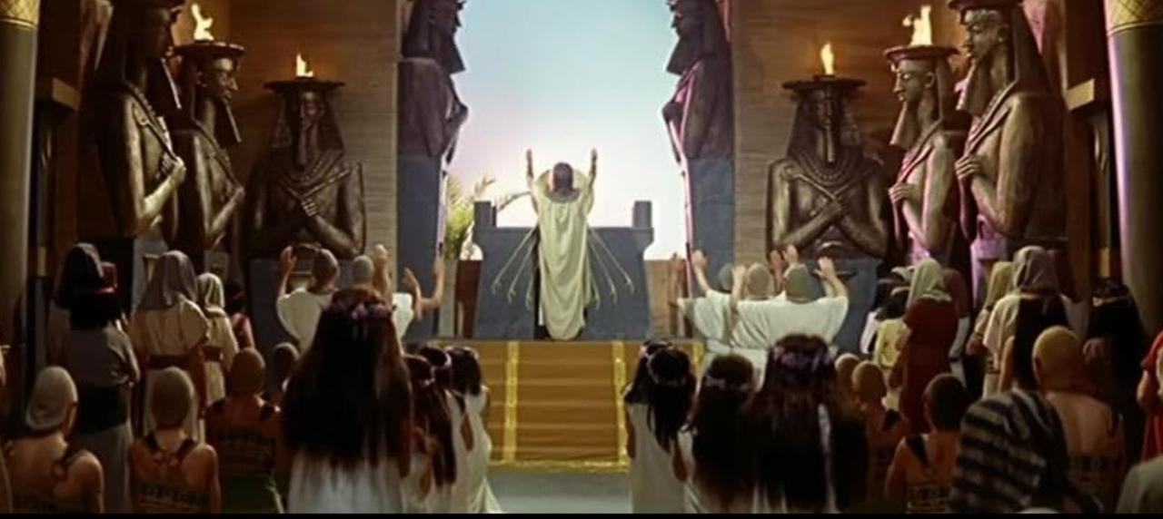 Eine Menschenmenge vor einem Altar in einem altägyptischen Tempel mit großen Statuen.