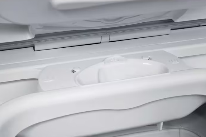 Zbliżenie na białą szufladę na detergent w pralce z przegródkami na proszek i płyn.