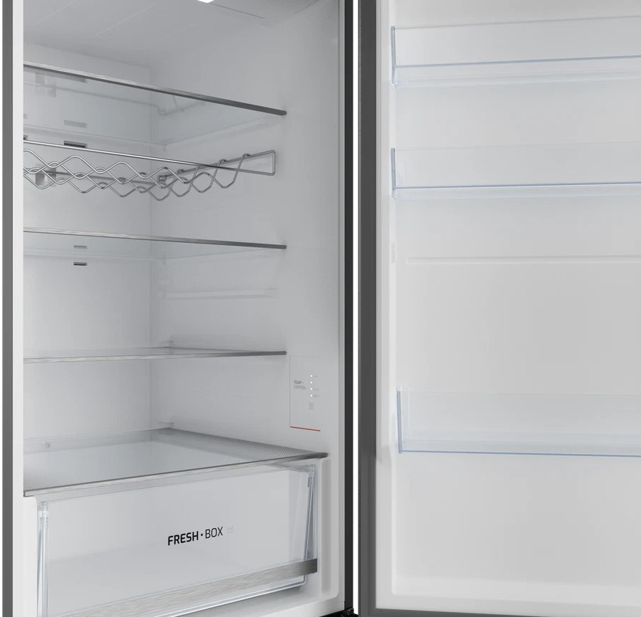Wnętrze pustej białej lodówki z szklanymi półkami, stojakiem na butelki i szufladą Fresh Box.