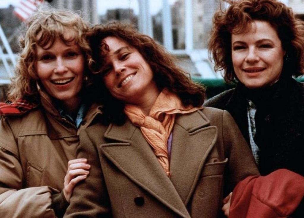 Drei glückliche Frauen in Wintermänteln lächeln im Freien.