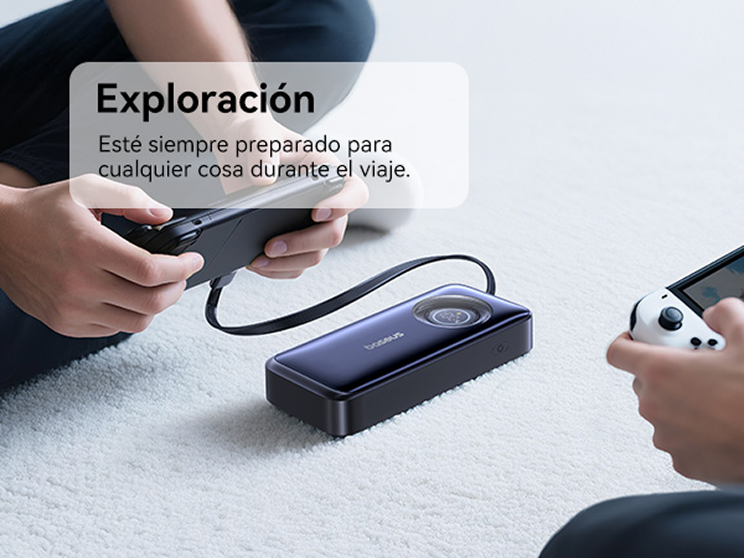 Personas juegan con consolas portátiles en una alfombra blanca, una se carga con una batería externa azul.