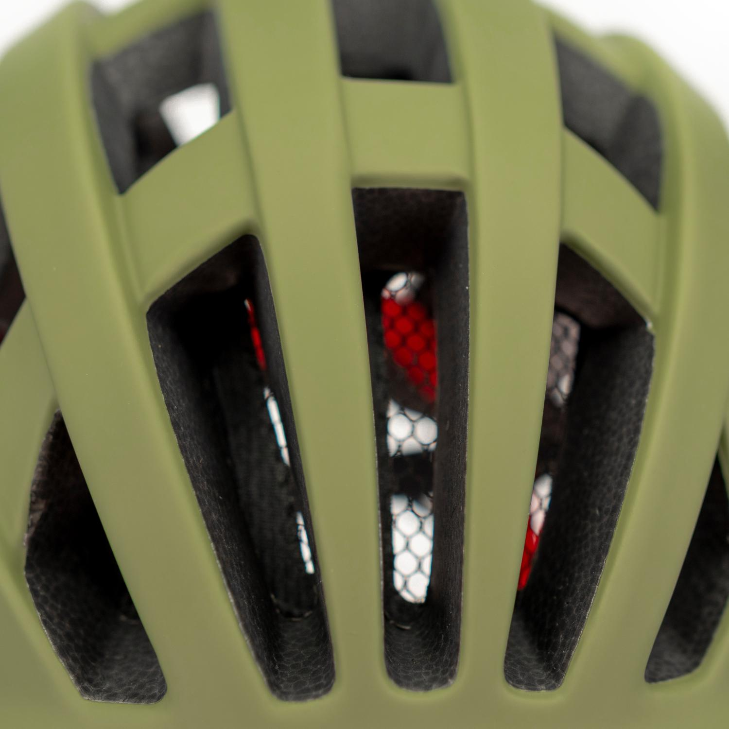 Primer plano de un casco de ciclismo verde oliva mate con grandes ranuras de ventilacion y malla roja.