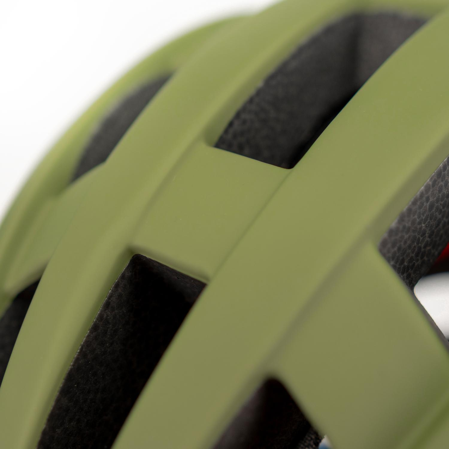 Primer plano de un casco de bicicleta verde oliva mate con agujeros de ventilación.