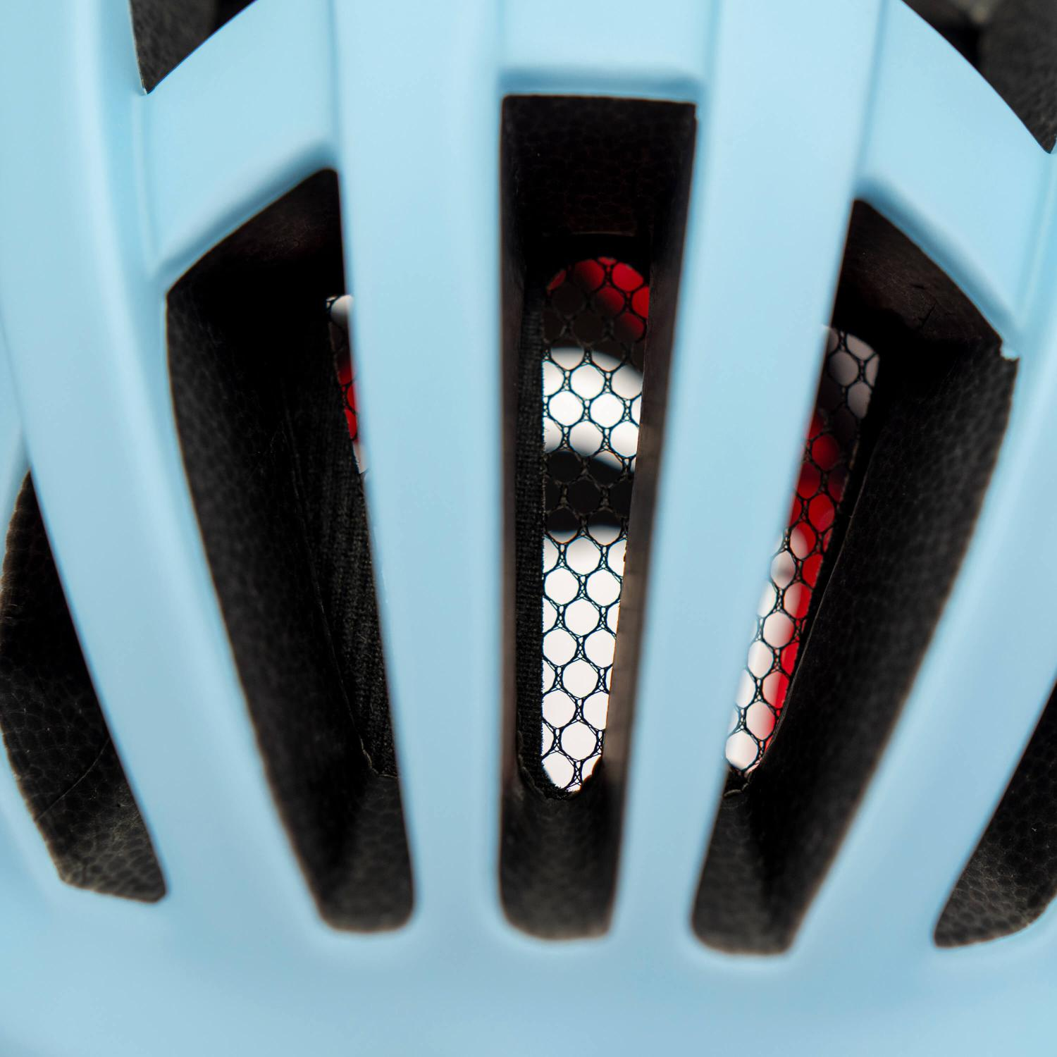 Primer plano de las aberturas de ventilación de un casco de bicicleta azul claro con malla negra.