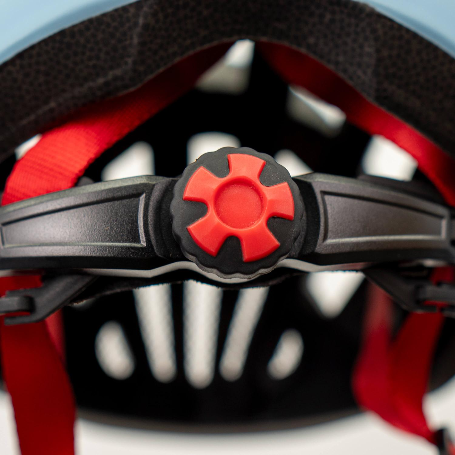 Primer plano de una rueda de ajuste roja en el interior de un casco de bicicleta negro.