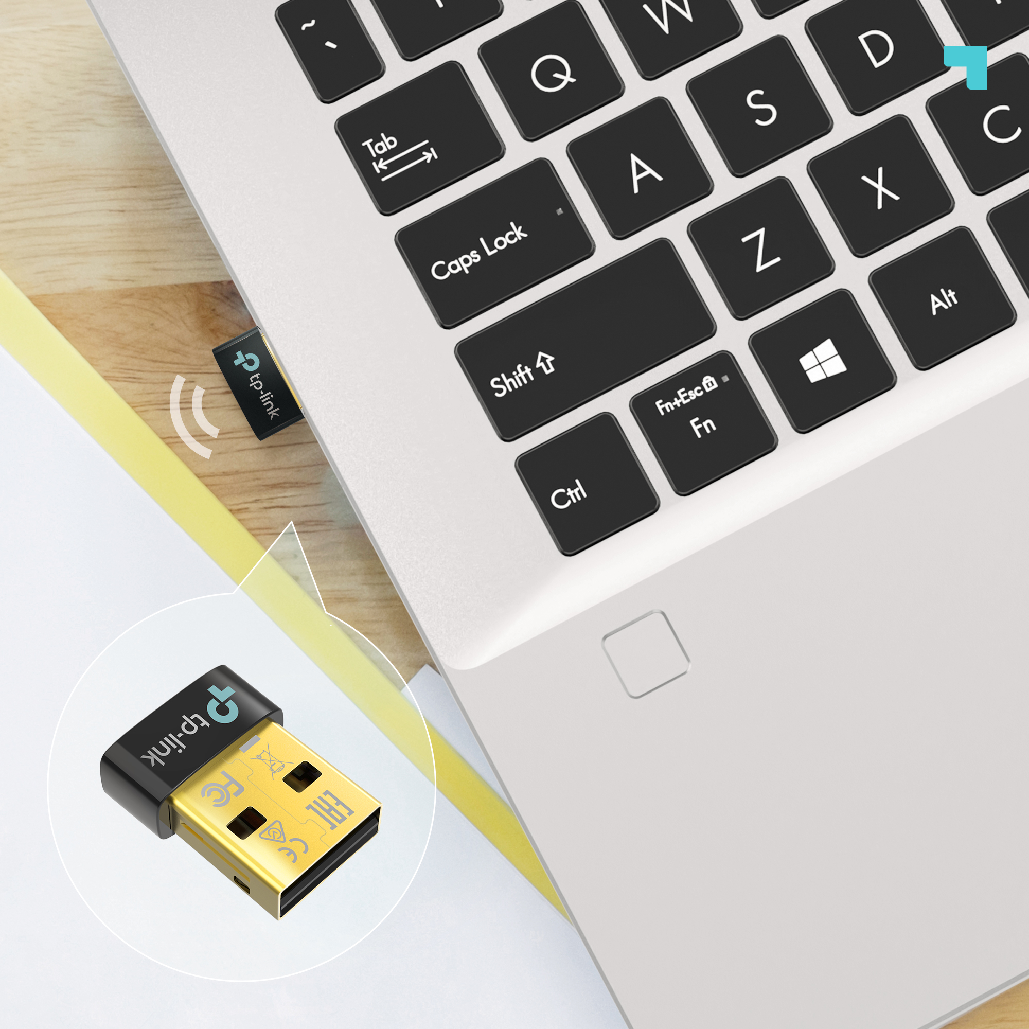 Un pequeño adaptador USB TP-Link conectado a una laptop plateada en un escritorio, con un recuadro de detalles.