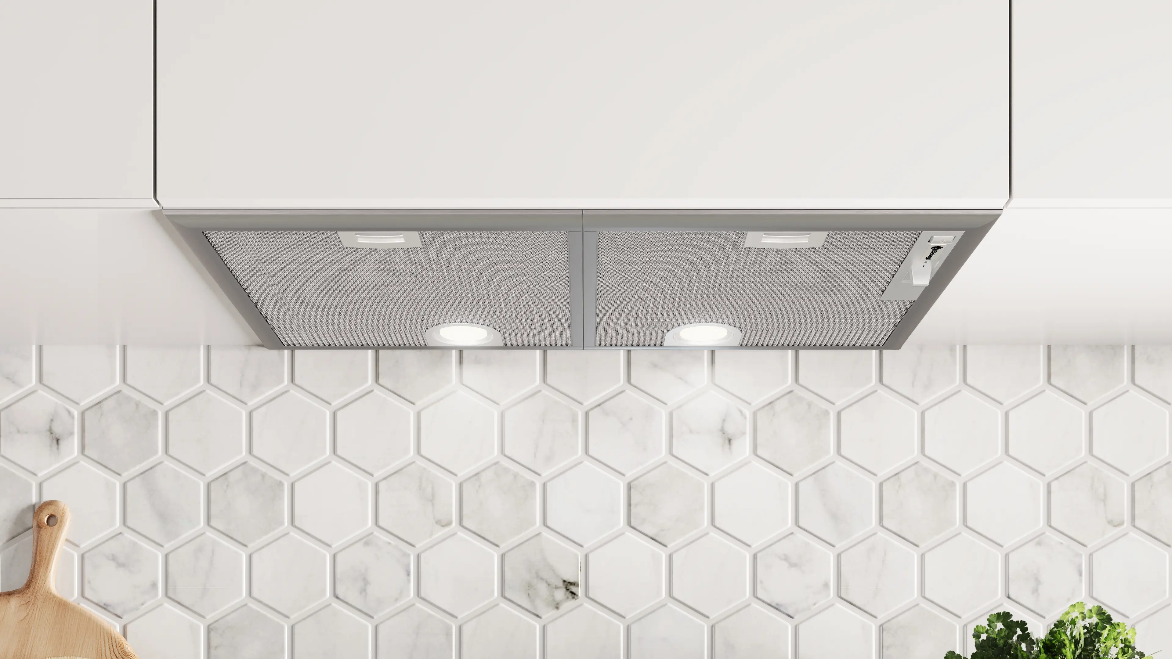 Una campana extractora de acero inoxidable bajo gabinetes blancos frente a una pared de azulejos hexagonales de mármol.