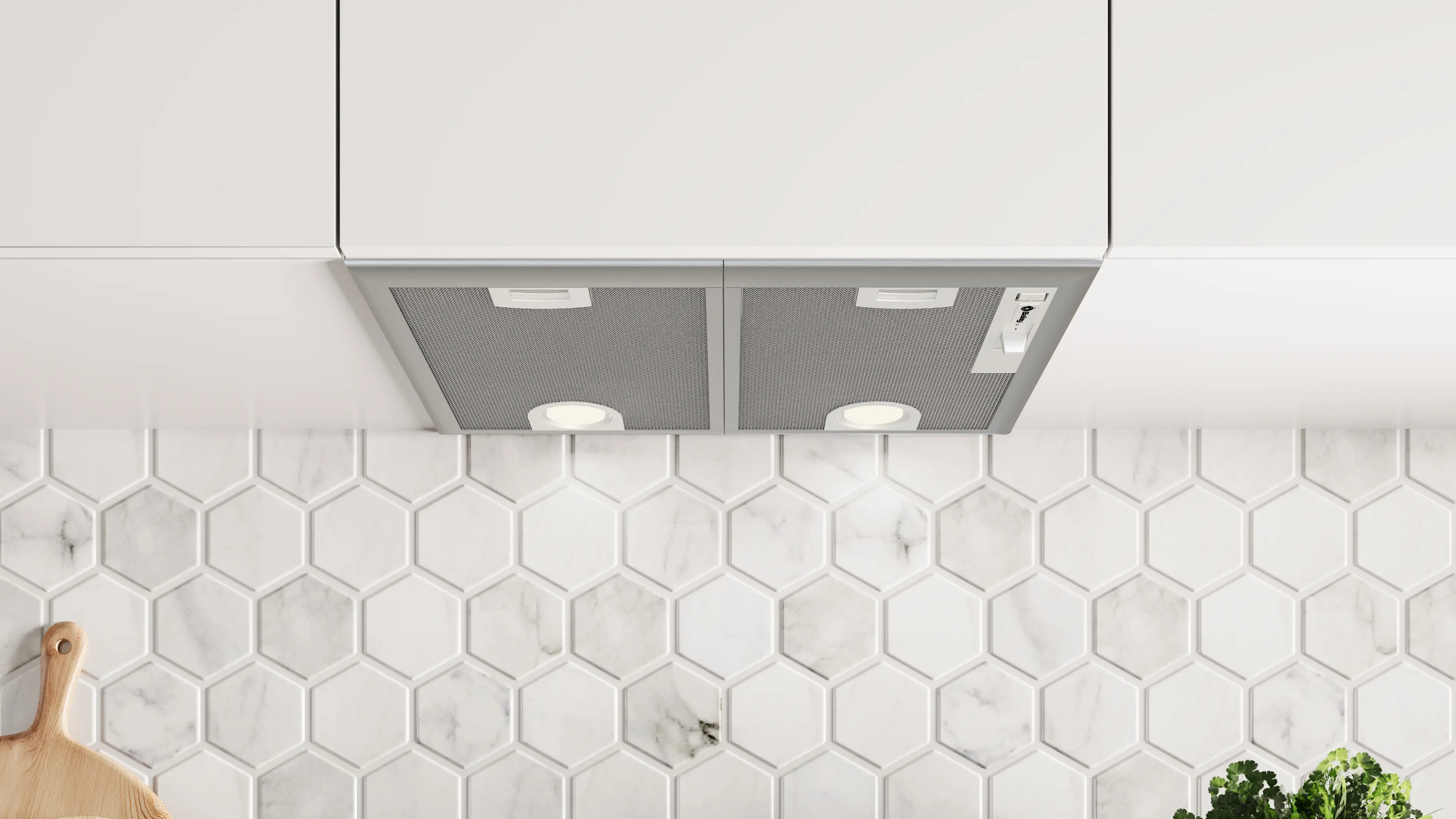 Campana extractora integrada bajo gabinetes blancos sobre una pared de azulejos hexagonales.