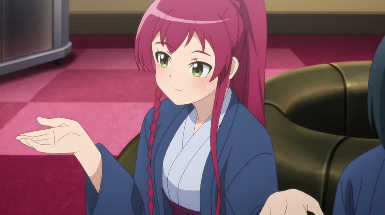 Ein Anime-Mädchen mit langen roten Haaren und blauen Kleidern spricht und gestikuliert in einem Raum.