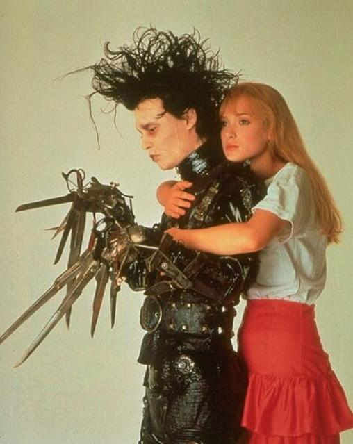 Edward mit den Scherenhänden steht mit Scheren als Händen neben einer blonden Frau, die ihn umarmt.