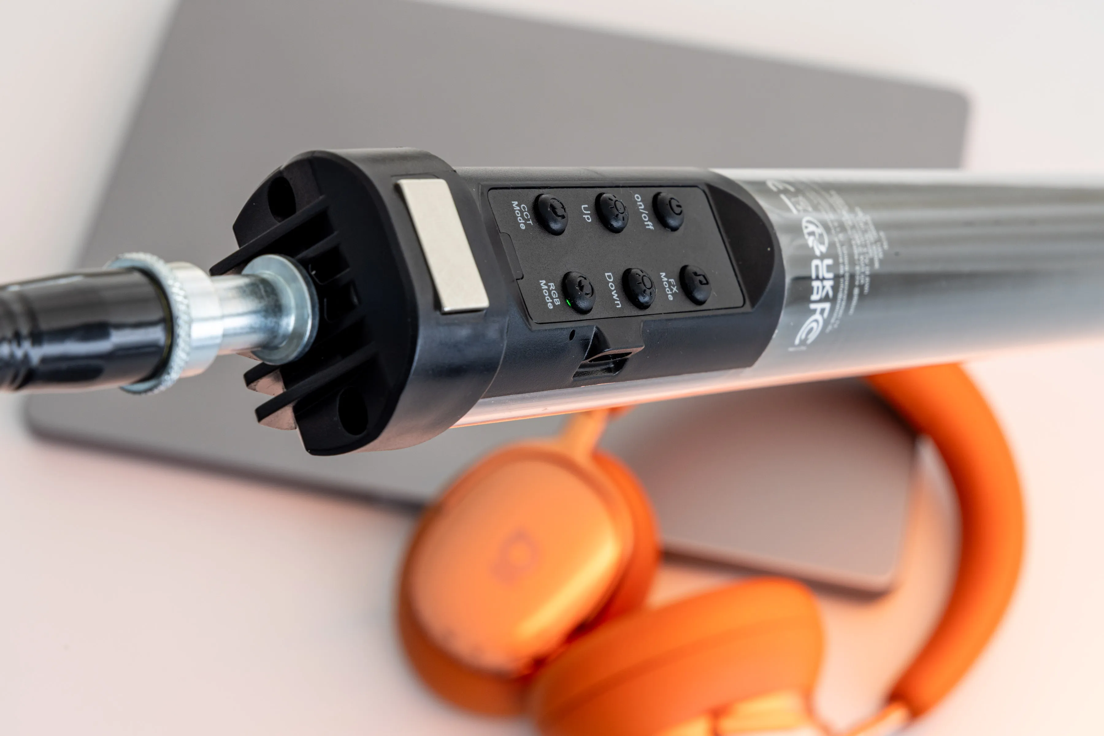 Bande lumineuse LED avec commandes, placée sur un ordinateur portable, avec un casque orange en arrière-plan.