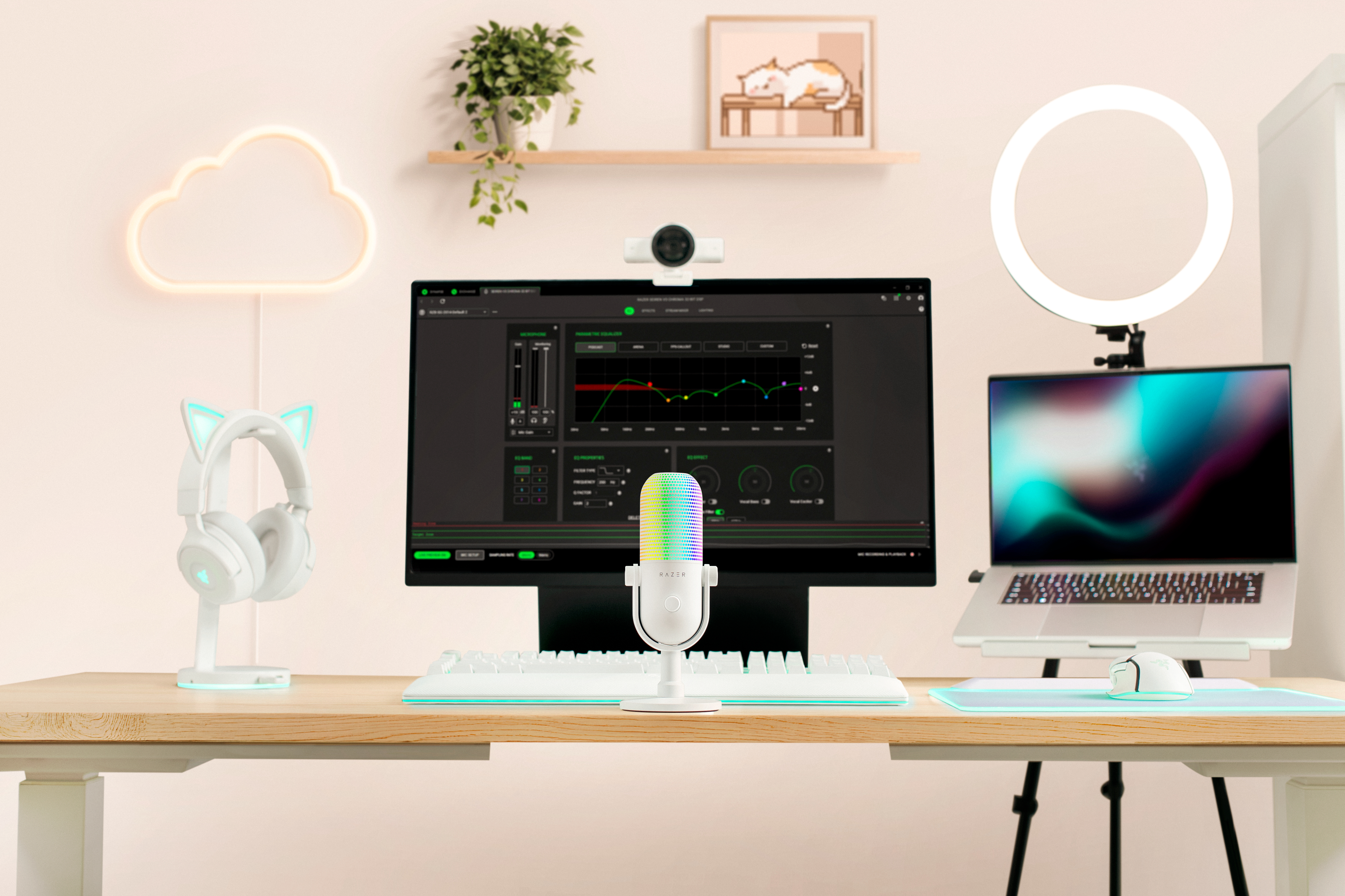 Ein weißer Gaming-Schreibtisch mit Monitor, Laptop, buntem Mikrofon, Katzenohren-Kopfhörern, Ringlicht und Wolken-Neonlicht.