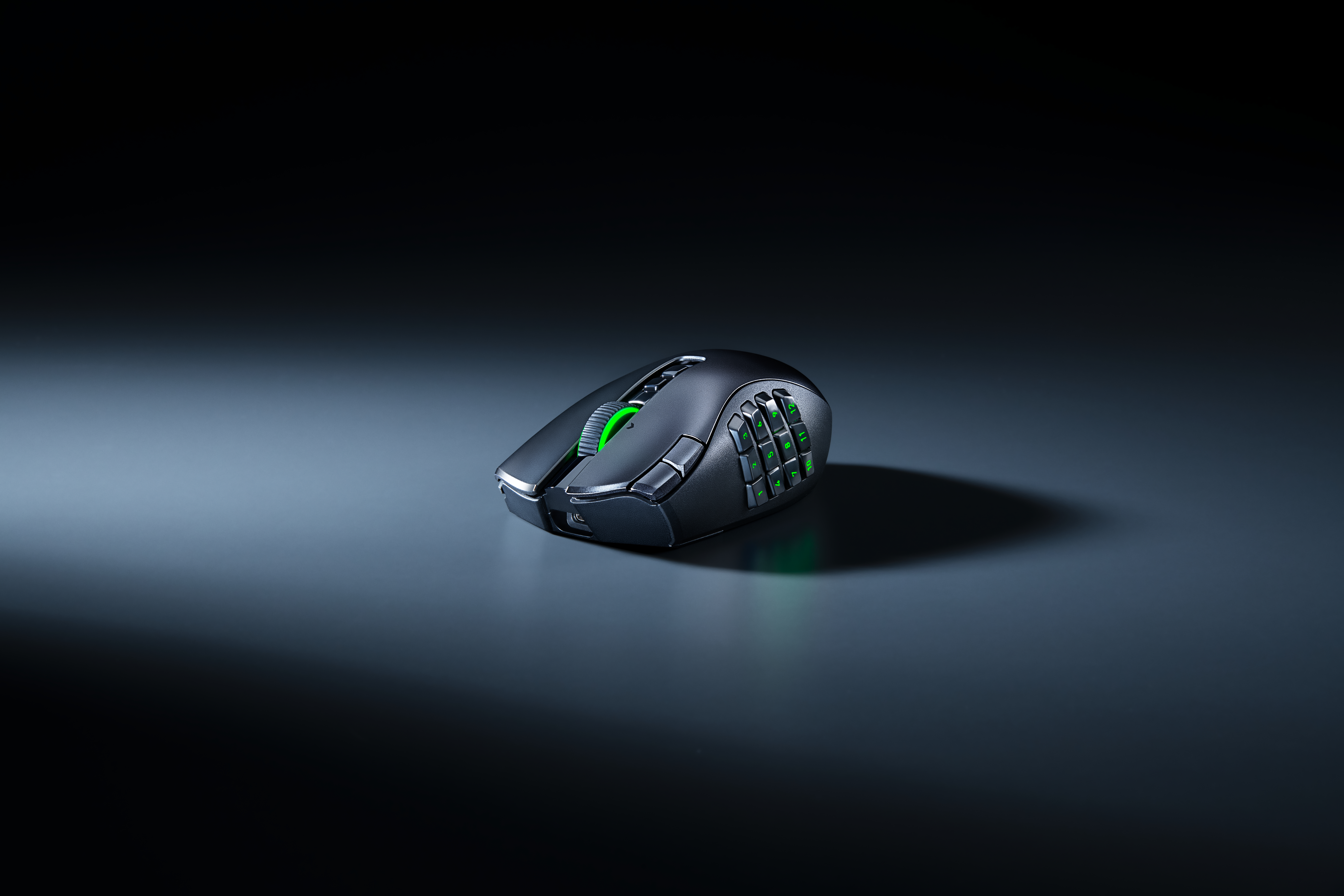 Eine schwarze Gaming-Maus mit grünem Leuchten auf einer dunklen Oberfläche.