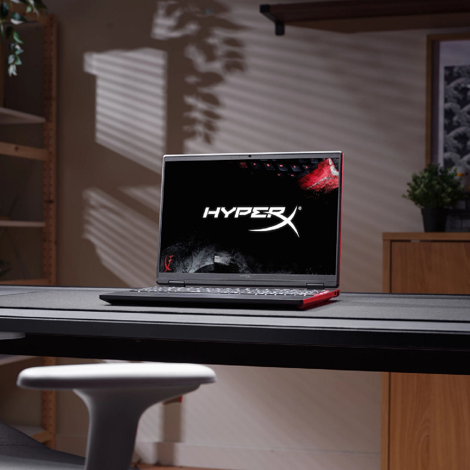 Un ordenador portátil con el logotipo de HyperX en la pantalla descansa sobre un escritorio.