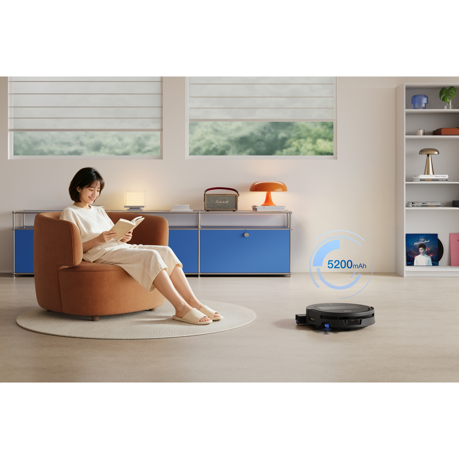 Una donna legge in poltrona mentre un robot aspirapolvere con batteria da 5200mAh pulisce il pavimento.