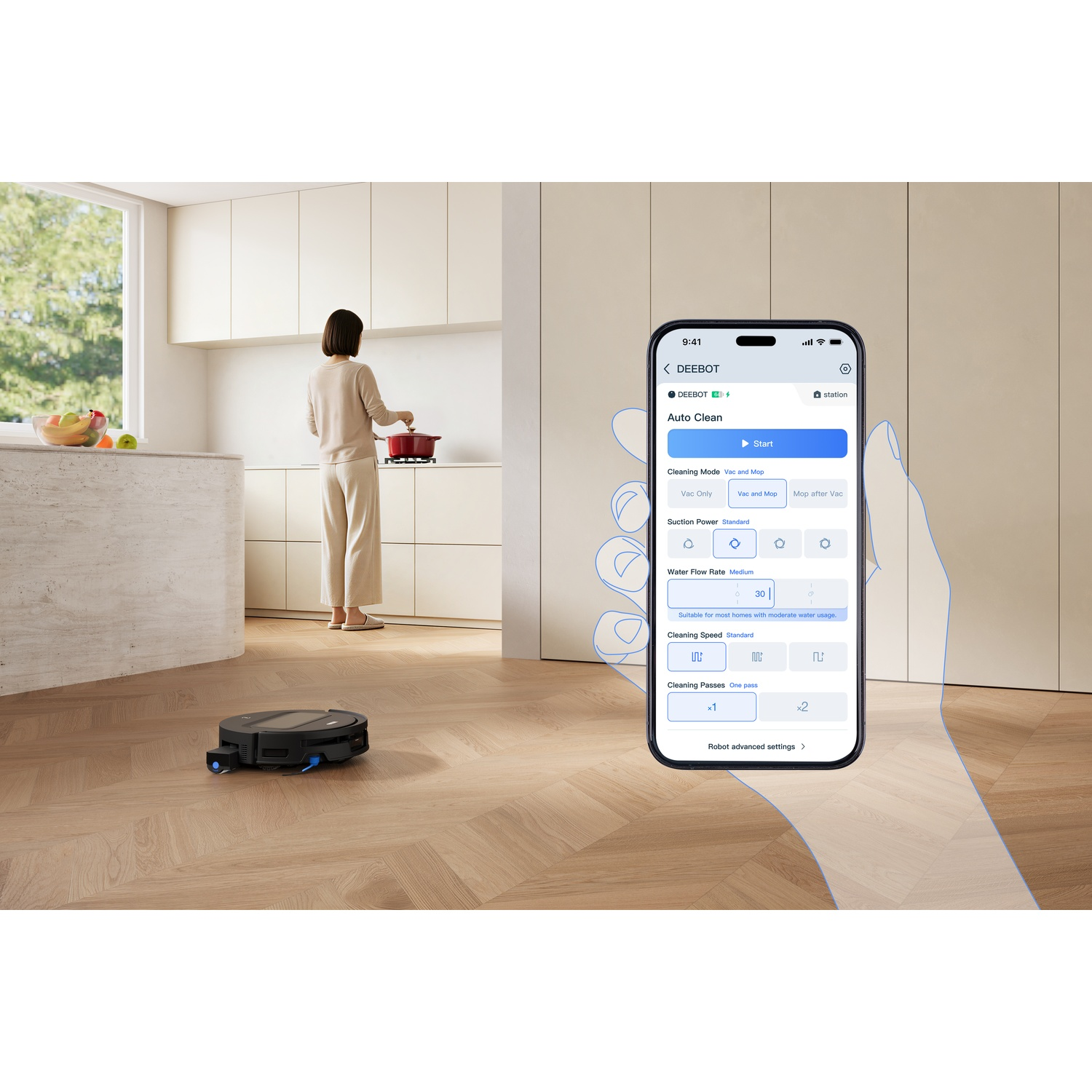 Mano regge smartphone con app di controllo mentre un robot aspirapolvere pulisce un pavimento in legno.