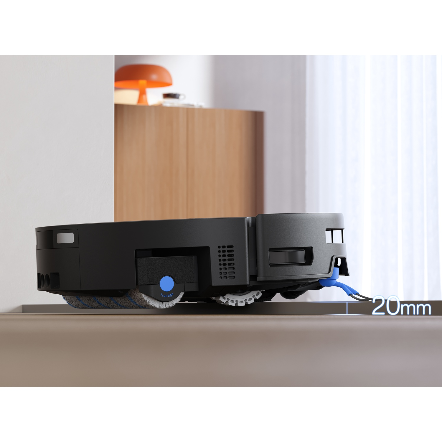 Robot aspirapolvere nero supera una soglia di 20 mm davanti a un mobile.