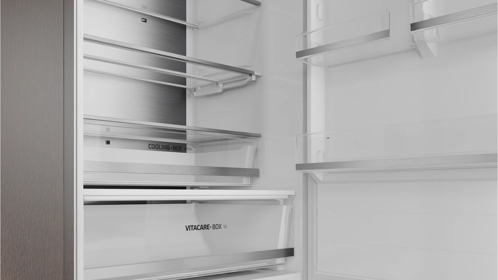 Wnętrze nowoczesnej, pustej lodówki z szklanymi półkami oraz dedykowanymi szufladami cooling i vitacare.