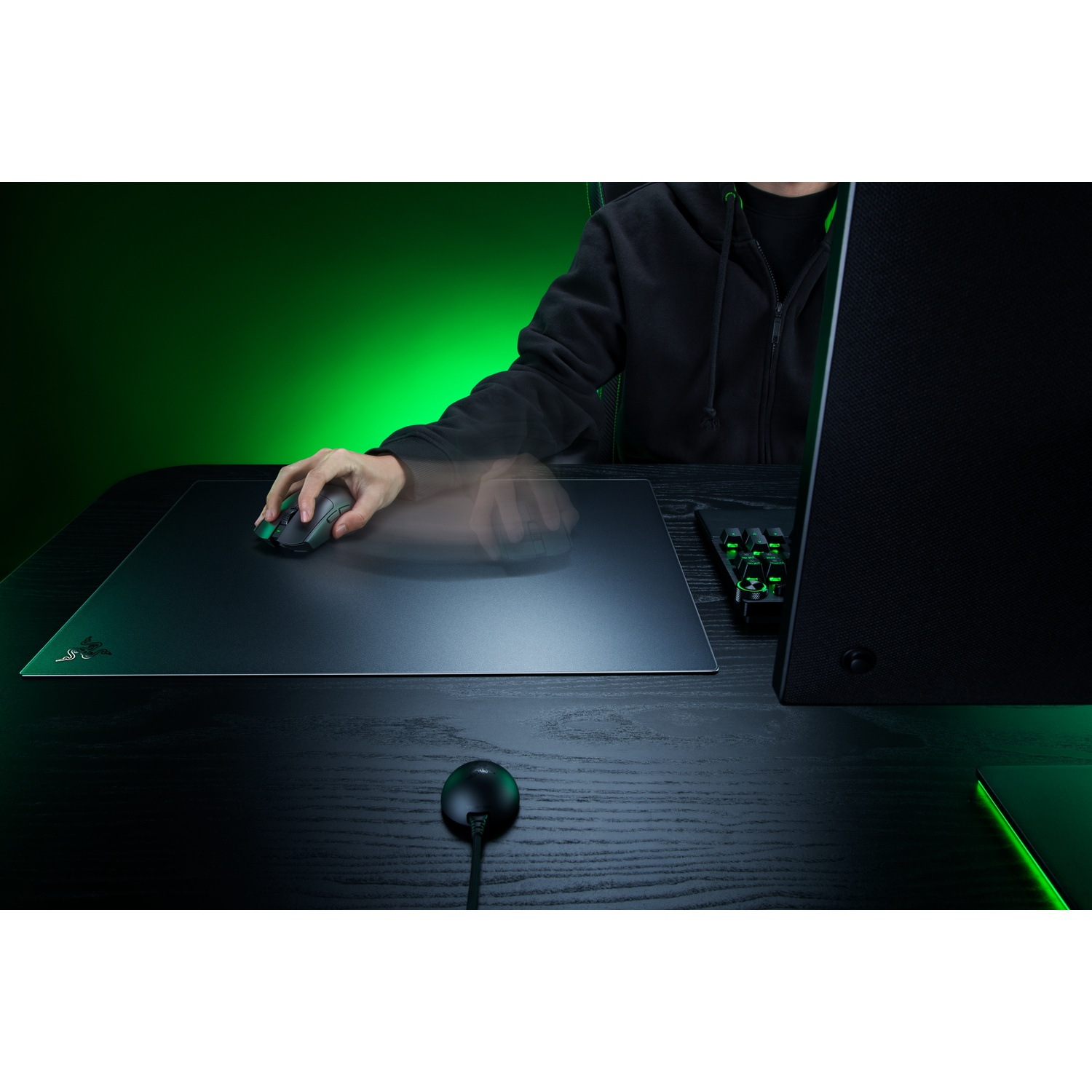 Persoon in zwarte hoodie gebruikt een gamingmuis op een muismat.