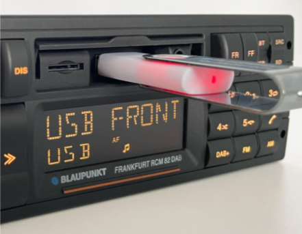 Zbliżenie radia samochodowego Blaupunkt z pendrivem w przednim porcie i napisem USB na ekranie.