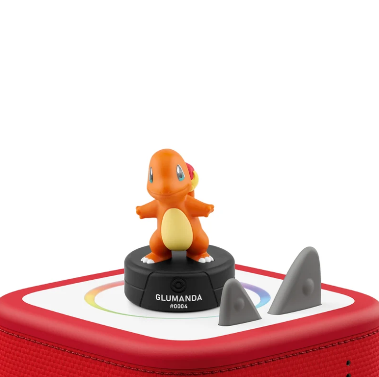 Eine orange Charmander-Figur steht auf einem schwarzen Sockel auf einem roten Lautsprecher.
