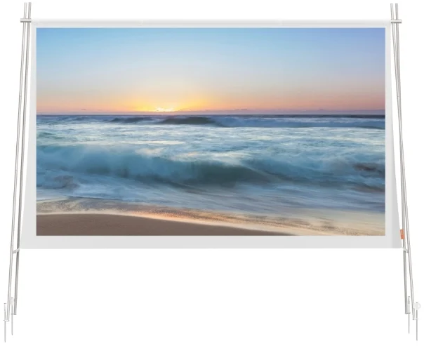 Eine Projektionswand auf einem Stativ zeigt eine Meereswelle bei Sonnenuntergang an einem Sandstrand.