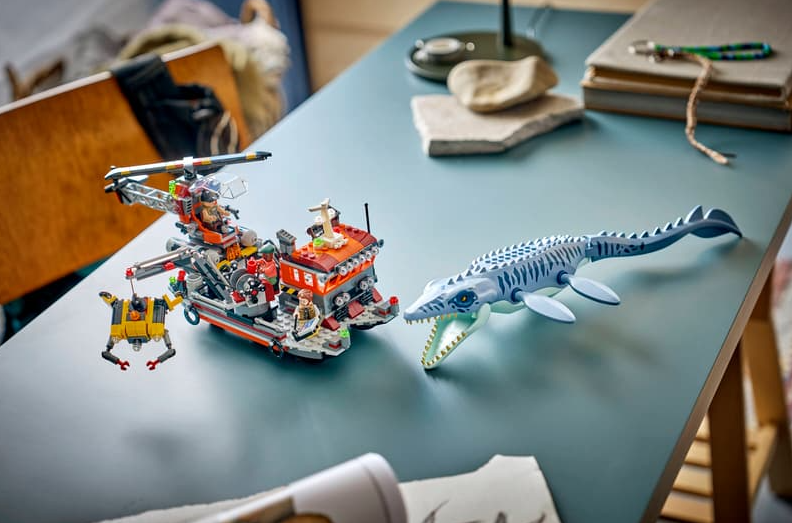 Ein Lego-Set auf einem blauen Tisch mit Forschungsboot, Helikopter und großem blauen Meeresreptil.