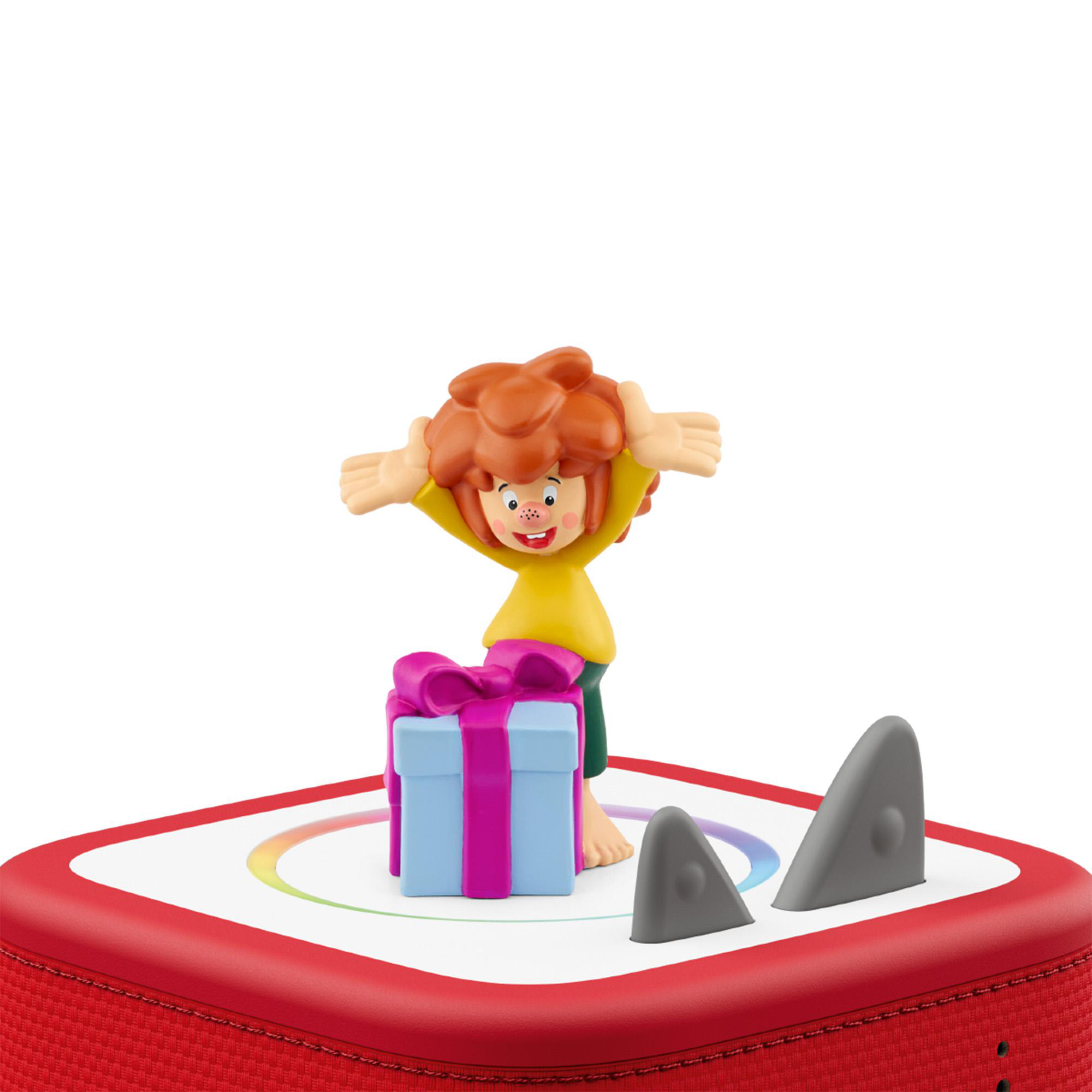Eine Pumuckl-Figur steht neben einem blauen Geschenk mit pinker Schleife auf einer roten Box mit Haifischflossen.