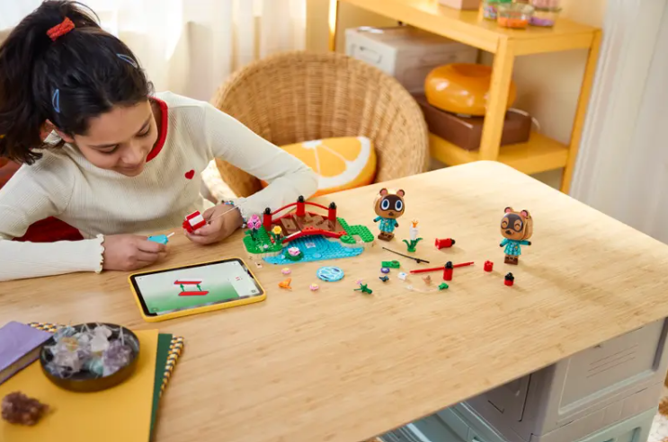 Ein Mädchen baut Animal Crossing-Lego an einem Holztisch mit Tablet.