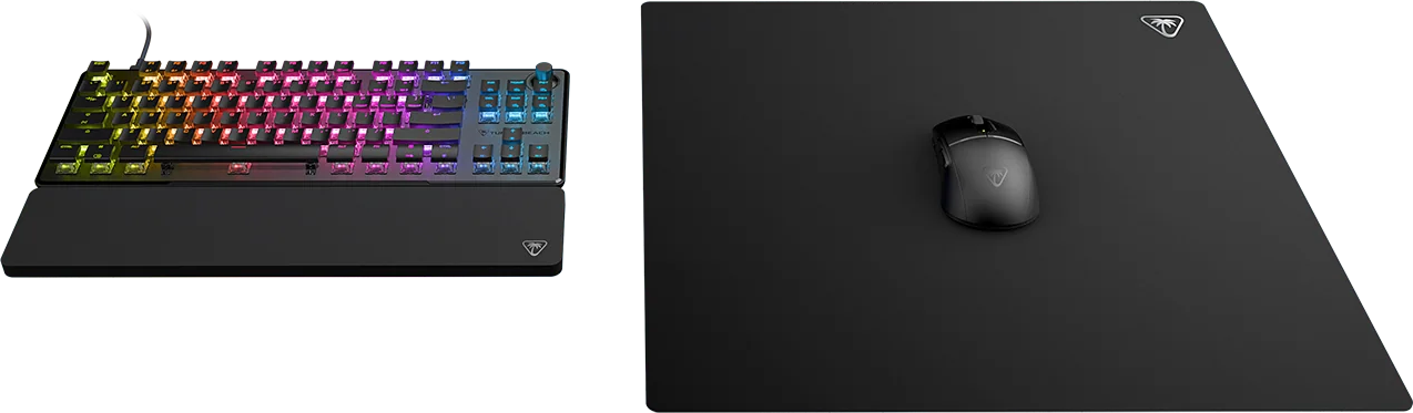 Clavier rétroéclairé RVB avec repose-poignet et souris noire sur tapis de souris sur fond noir.